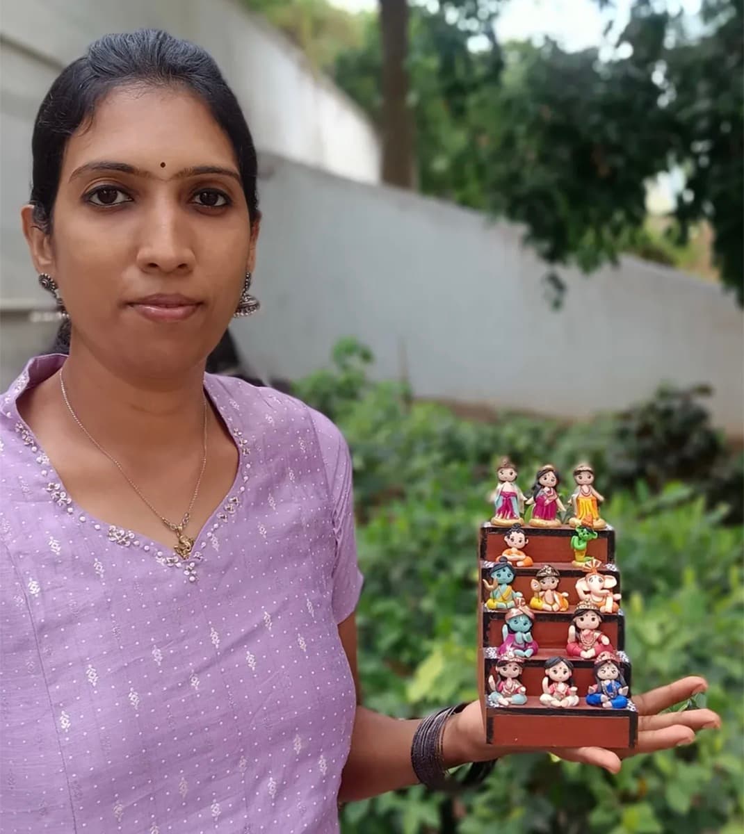 Indira holding a set of miniature clay figures she made